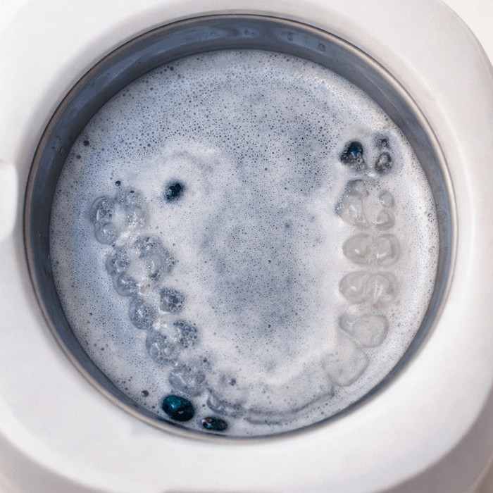 Ultrasonic Dental Cleaner with a circular component filled with bubbling blue liquid on a white background